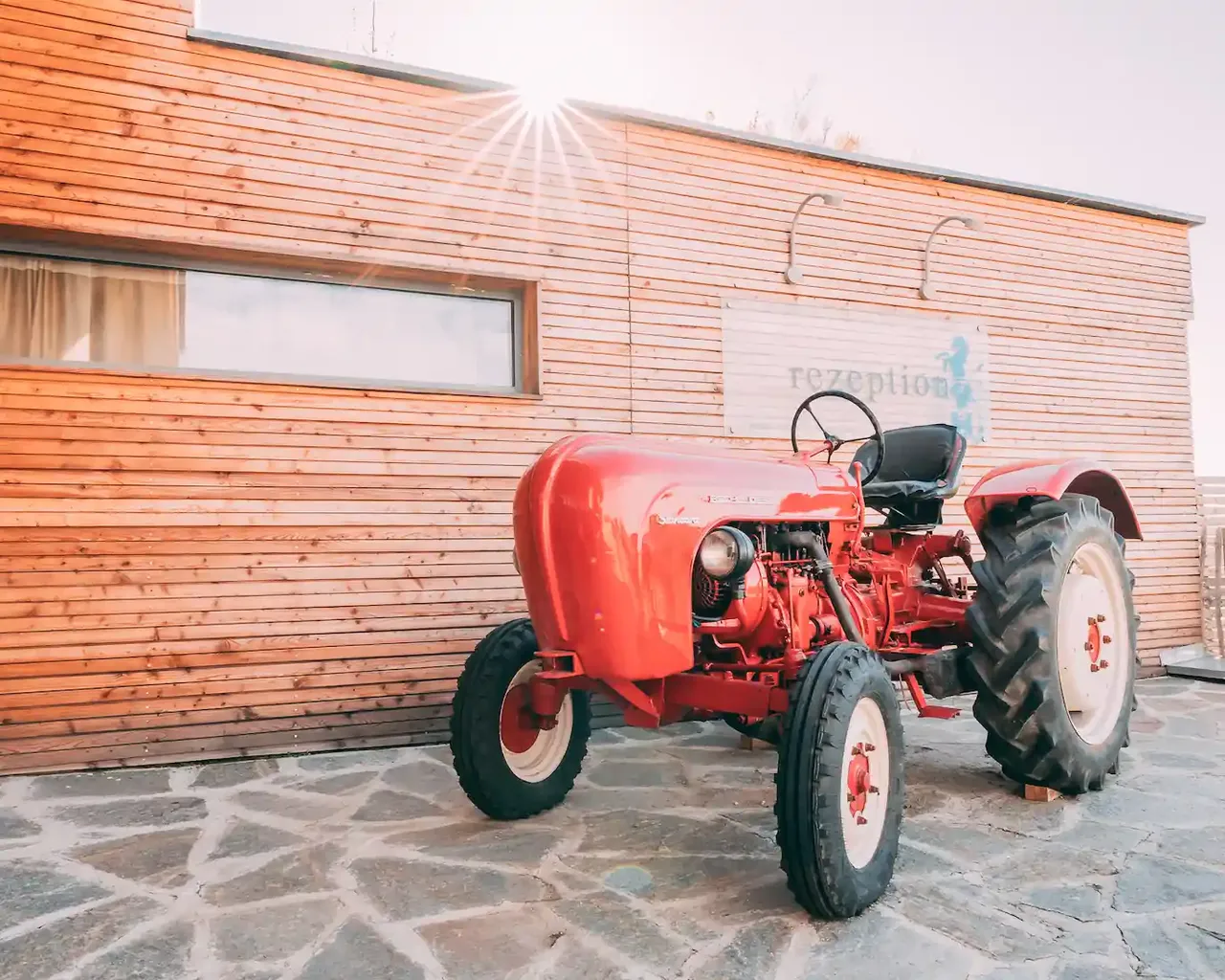 Röd traktor framför receptionen på Gut Hügle